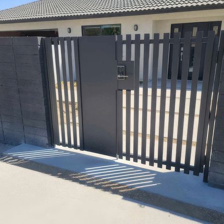 A black fence with a gate in front of a house