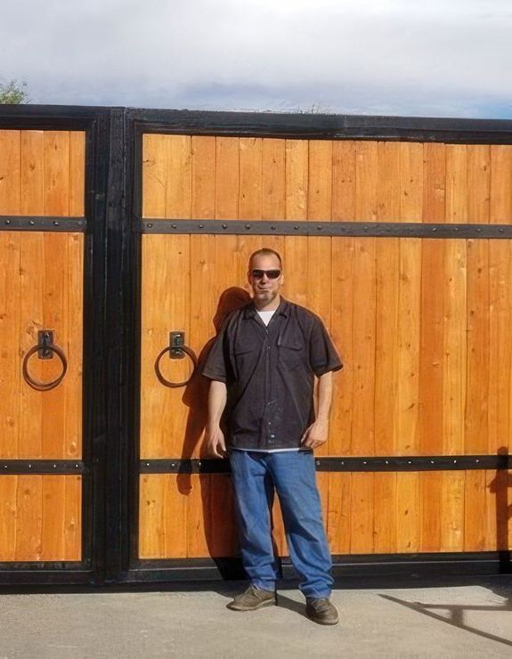 A man is standing in front of a wooden gate