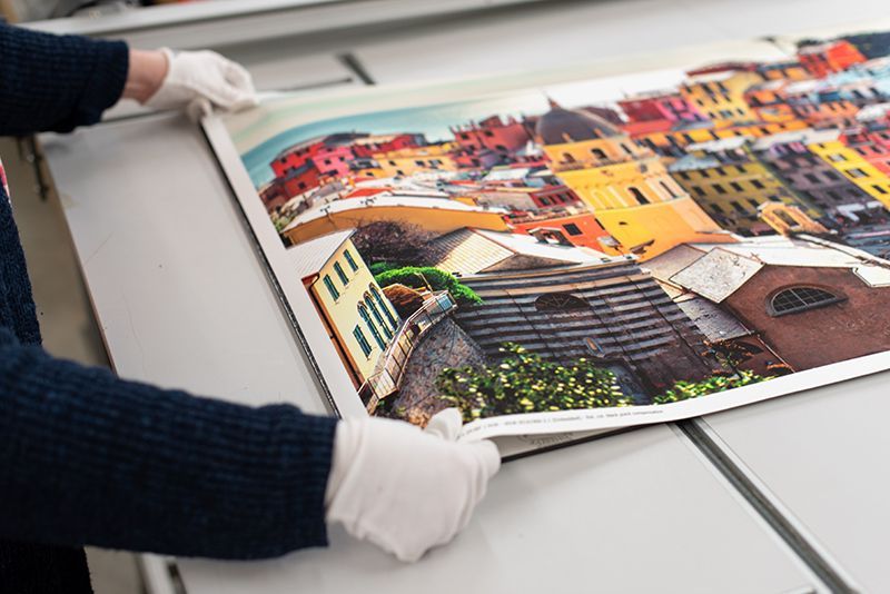A photo of white-gloved employee laying a large photo print out.