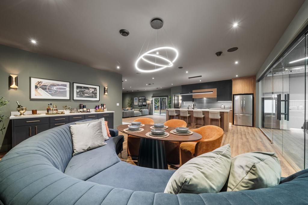 Modern conference room with curved blue sofa, round table, orange chairs, and glass walls