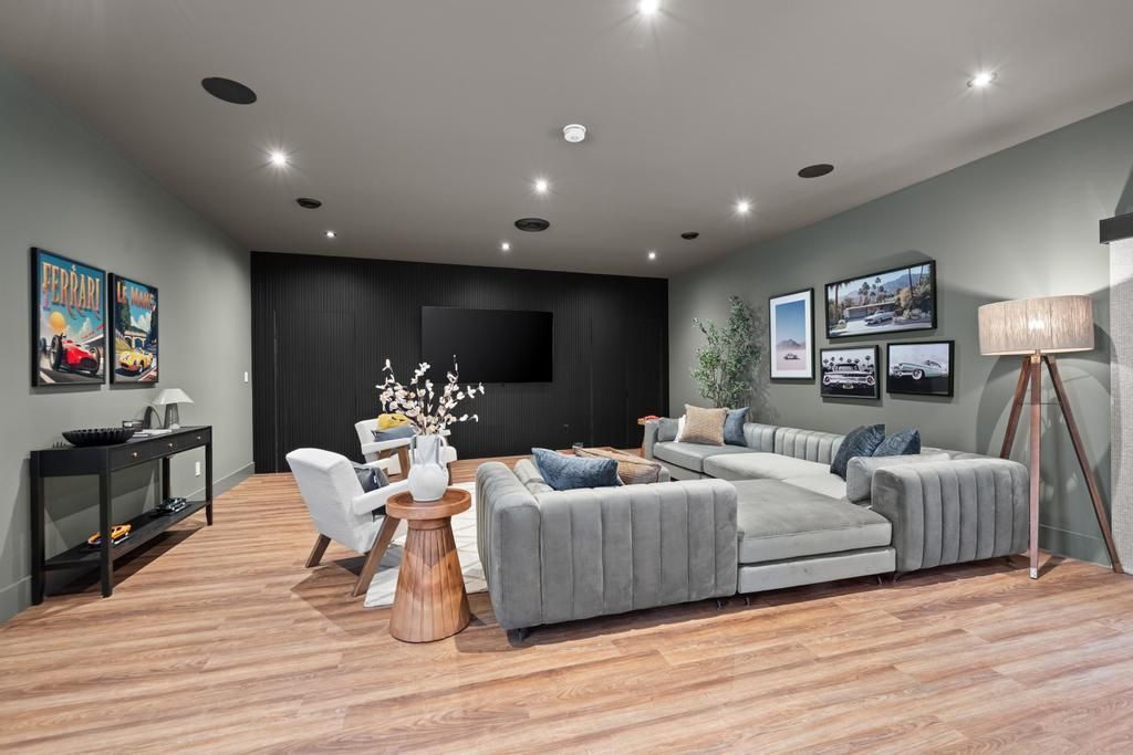 Modern living room with gray sectional sofa, wood floors, wall art, and a console table with flowers