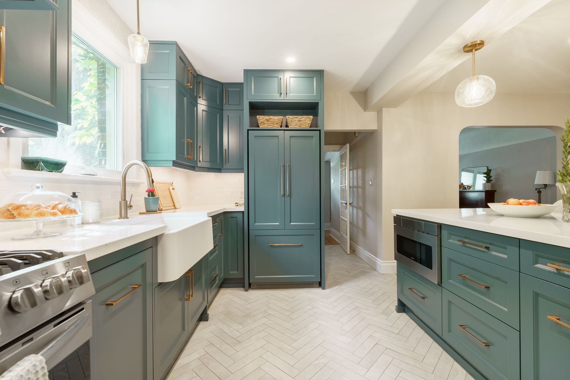 Teal kitchen with white countertops, stainless stove, island, and bright window light