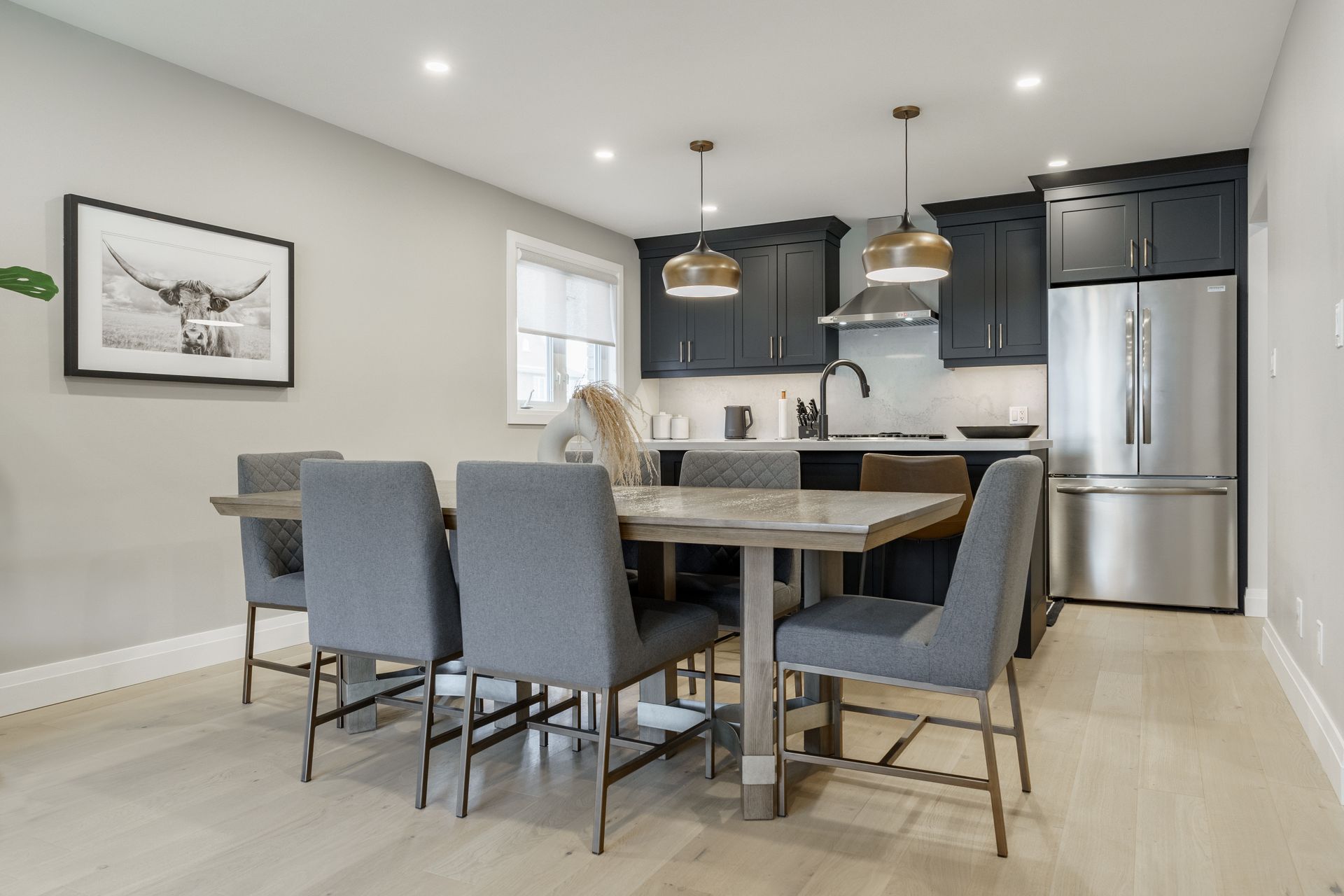 Modern kitchen sink with black faucet, white countertop, and pendant lights over an island.