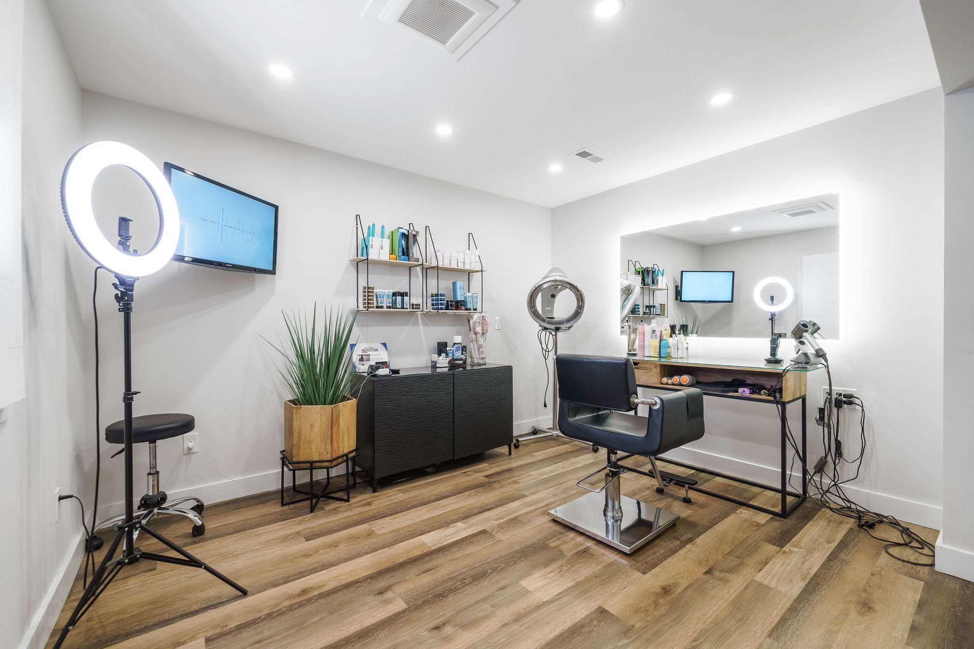 Modern living room with orange chairs, blue sofa, wall-mounted TV, and a ceiling light fixture
