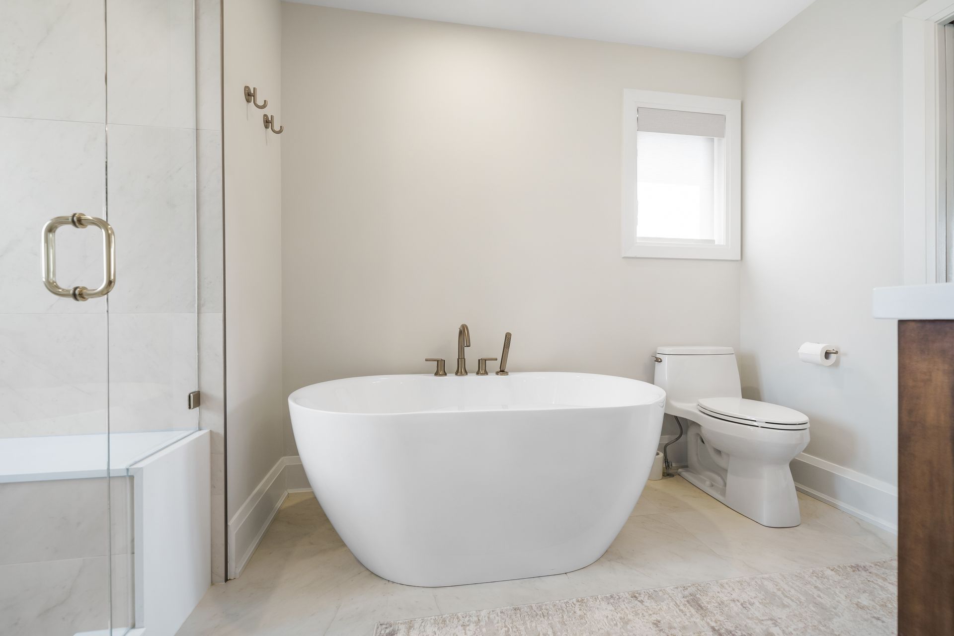 Compact white bathroom with wooden vanity, round mirror, toilet, and black-and-white floor tiles.