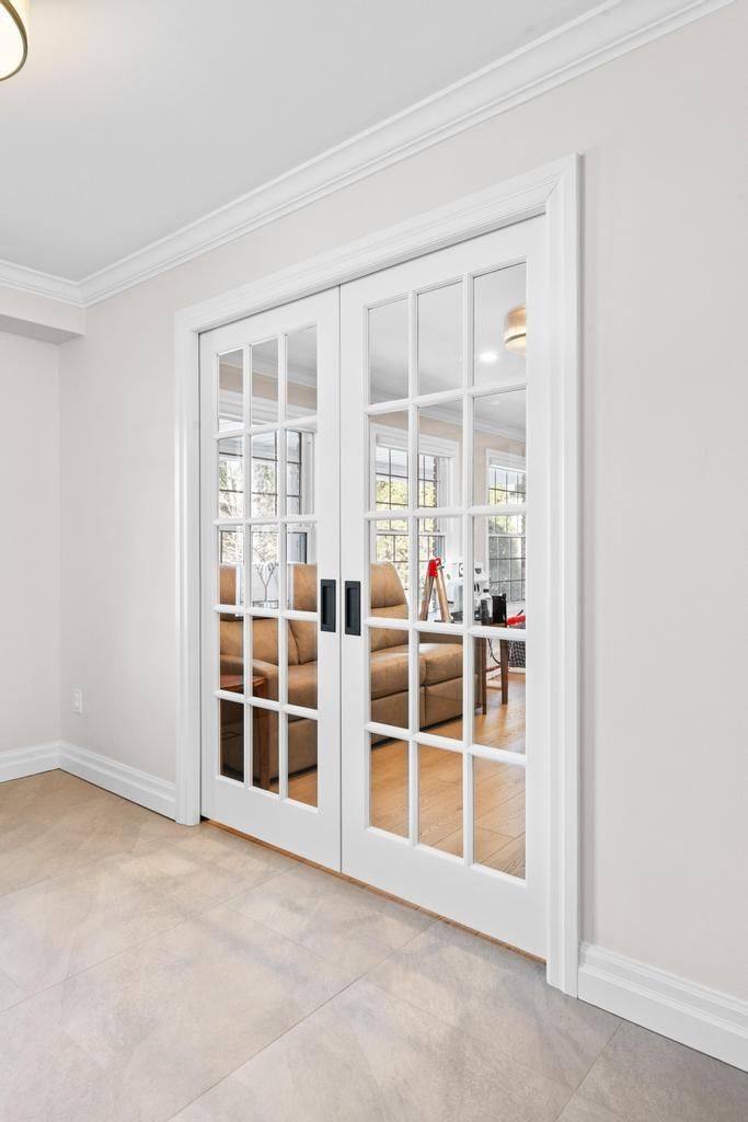 White French doors with glass panes in a bright, modern room with light tile flooring.