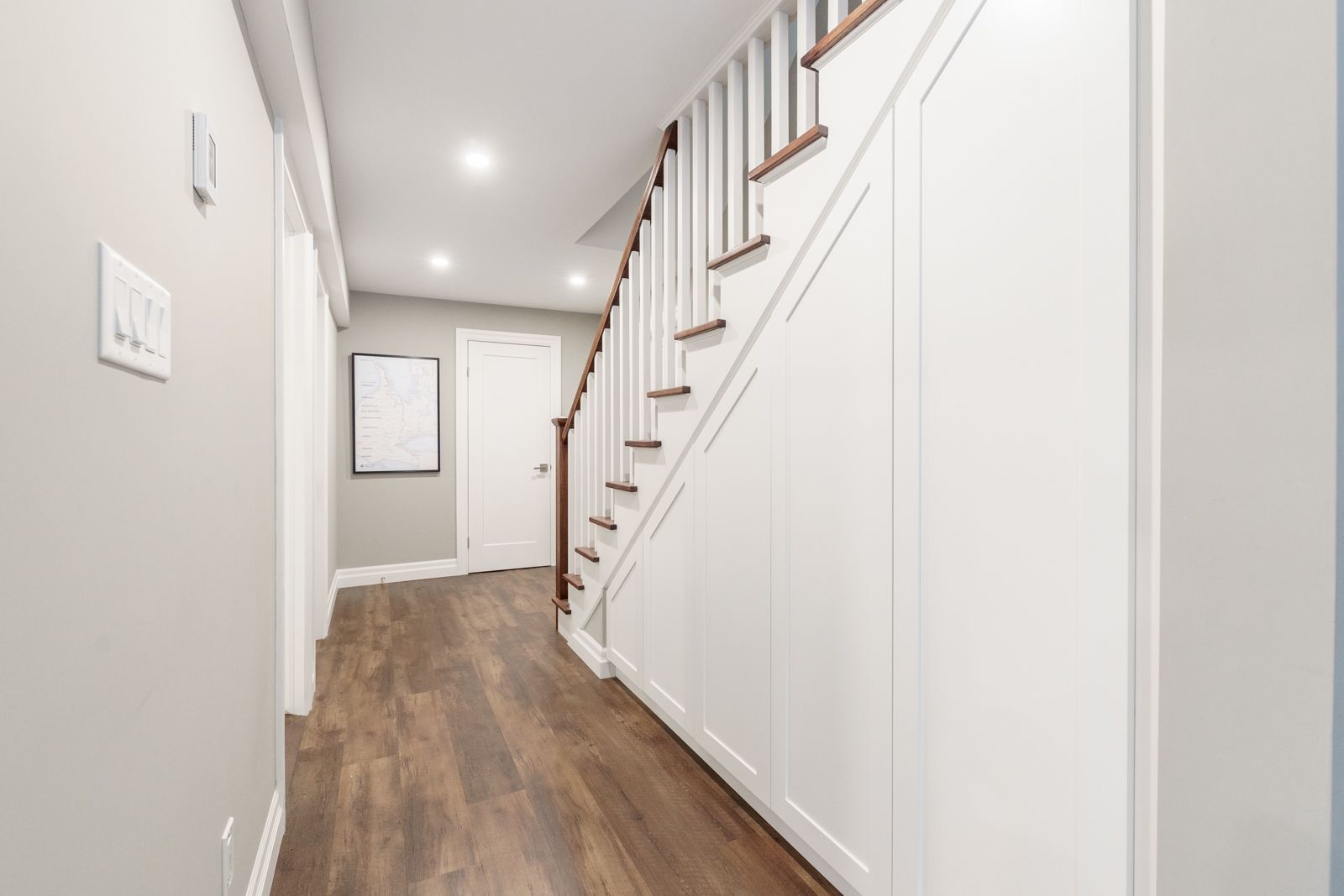 Empty white elevator interior with light wood floor, control panel, and handrail.
