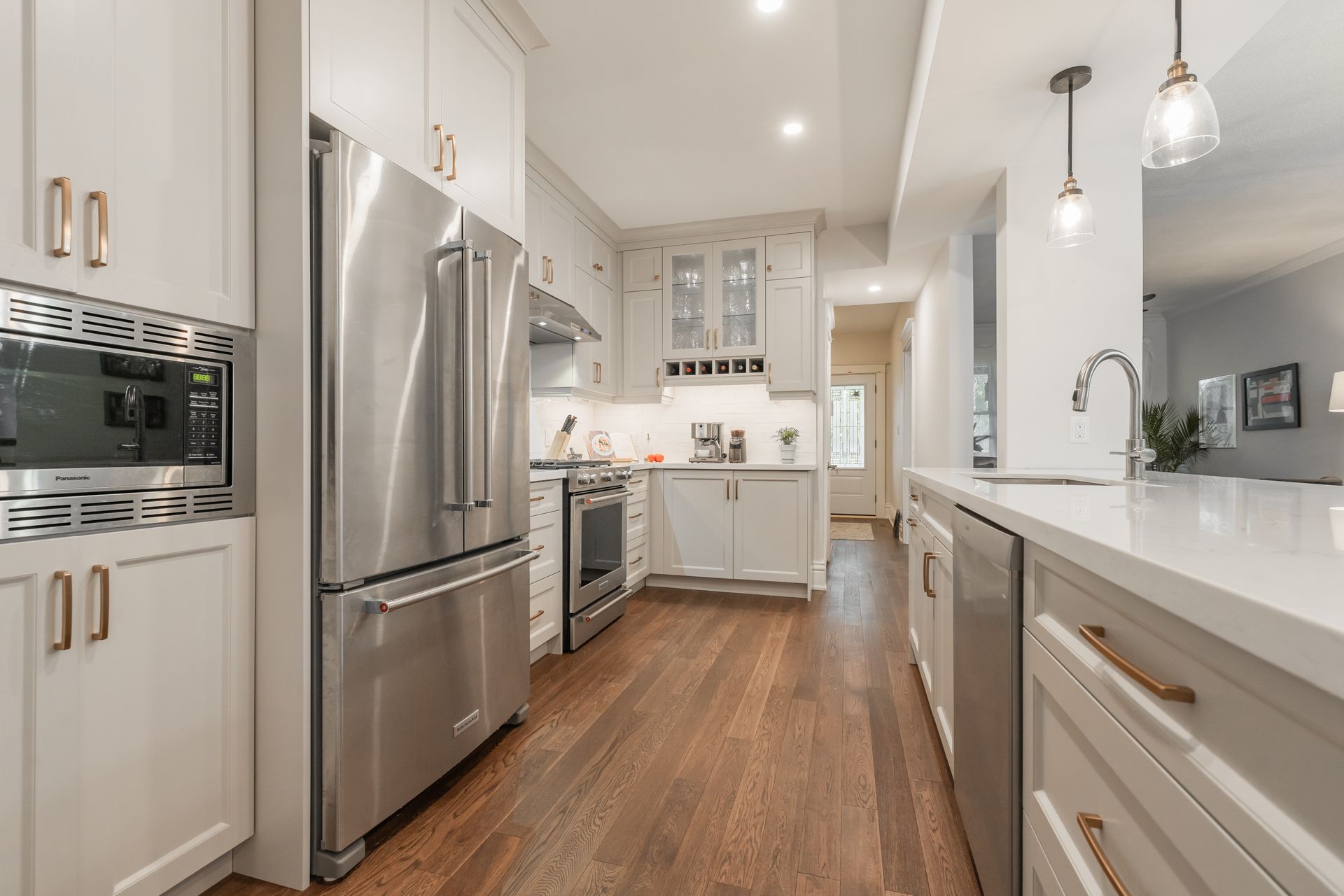 Bright modern kitchen with white cabinets, stainless steel appliances, and a long island with pendant lights.