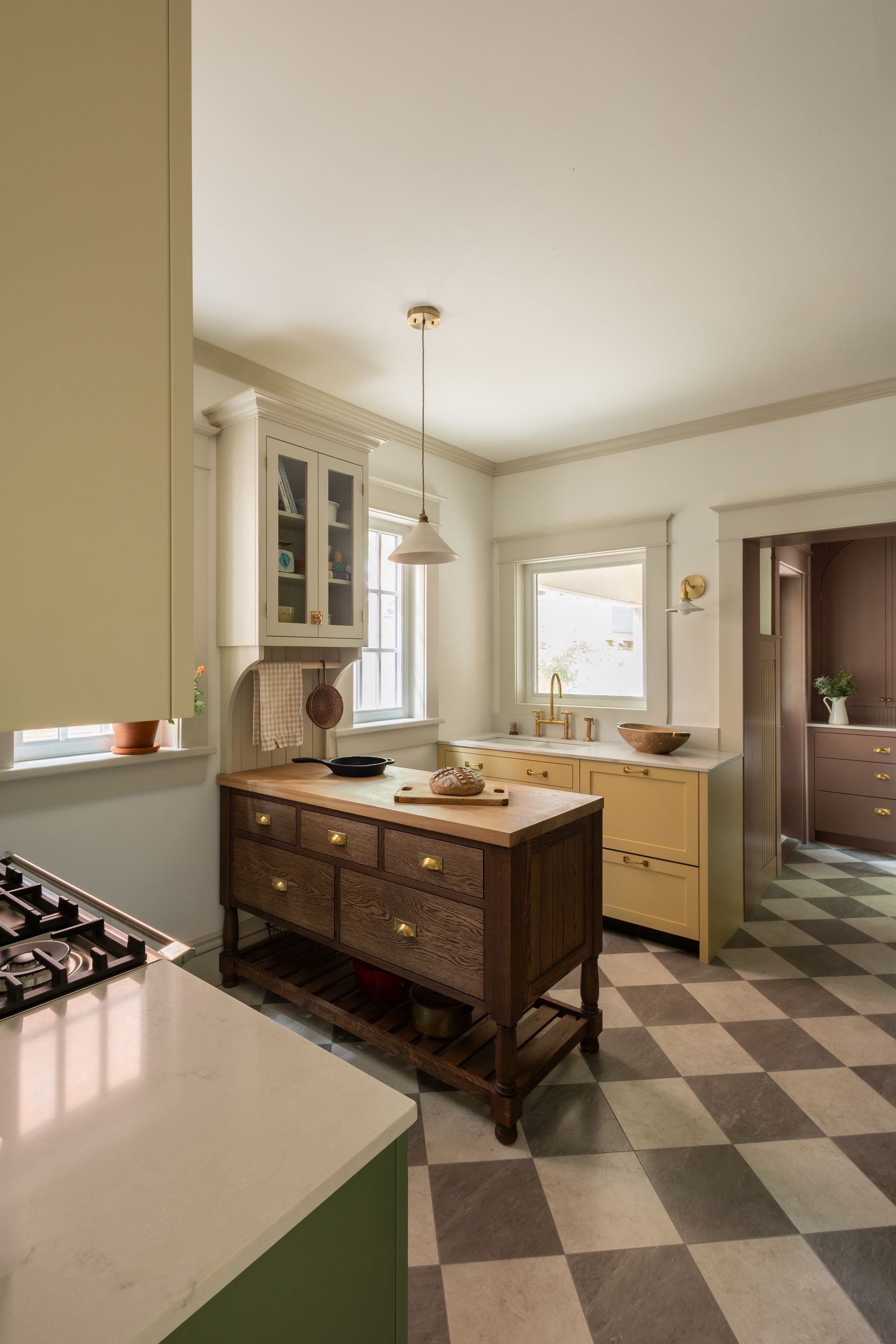 Bright vintage kitchen with checkered floor, white cabinets, and a central island under pendant lights