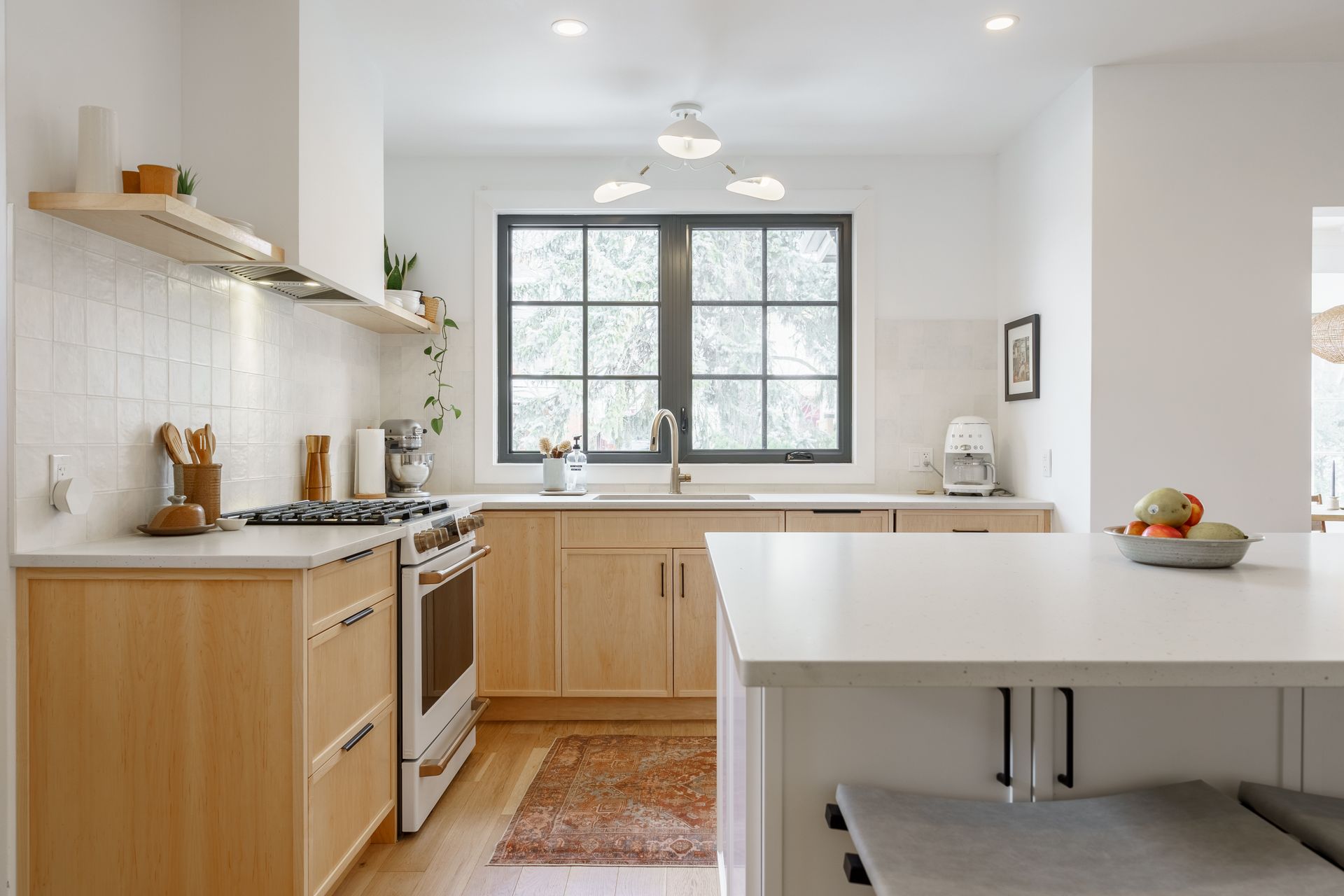 Bright modern kitchen with white counters, wood cabinets, and a window over the sink