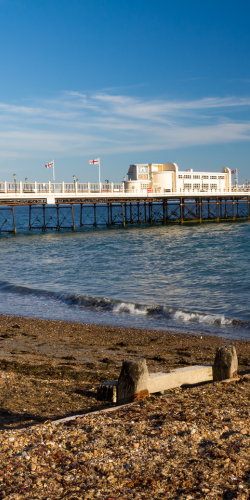 There is a pier in the background and a beach in the foreground.