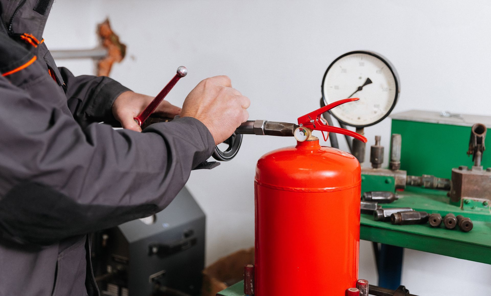 Technician performing a fire extinguisher recharge on a red cylinder