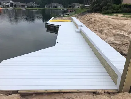 A white dock is sitting next to a body of water.