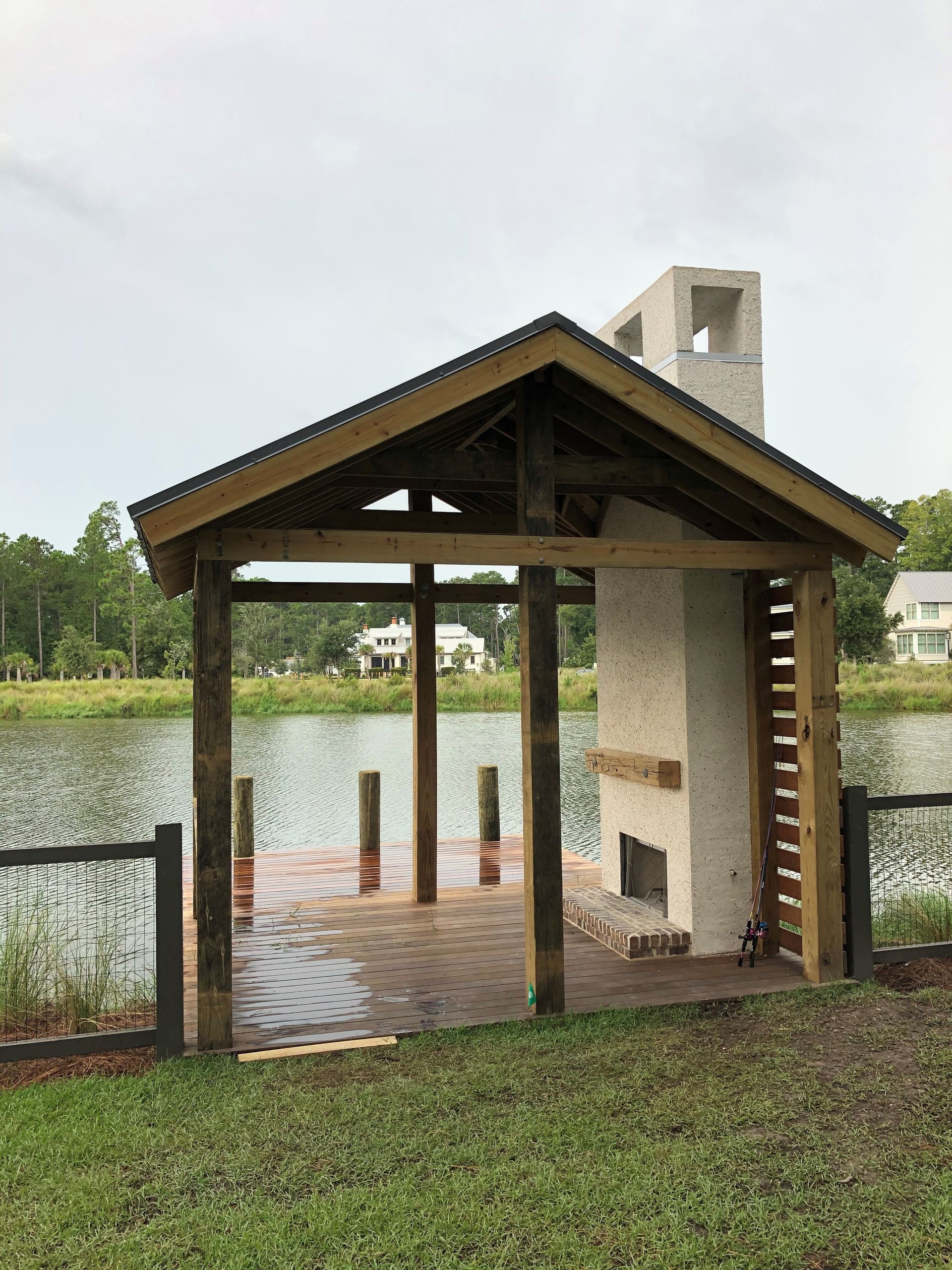 A pavilion with a fireplace and a dock next to a lake.