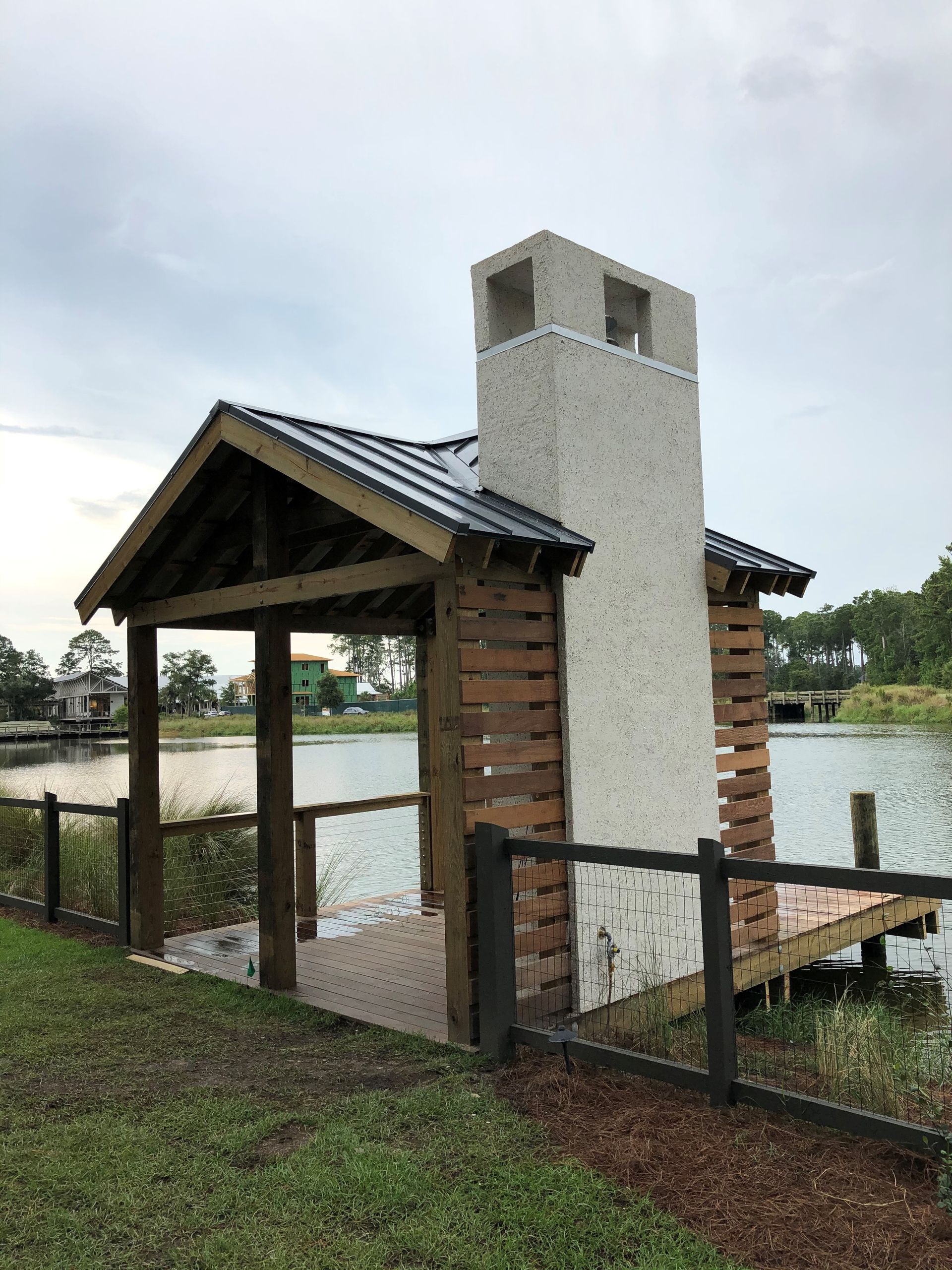 A small house with a chimney on the side of it next to a body of water.