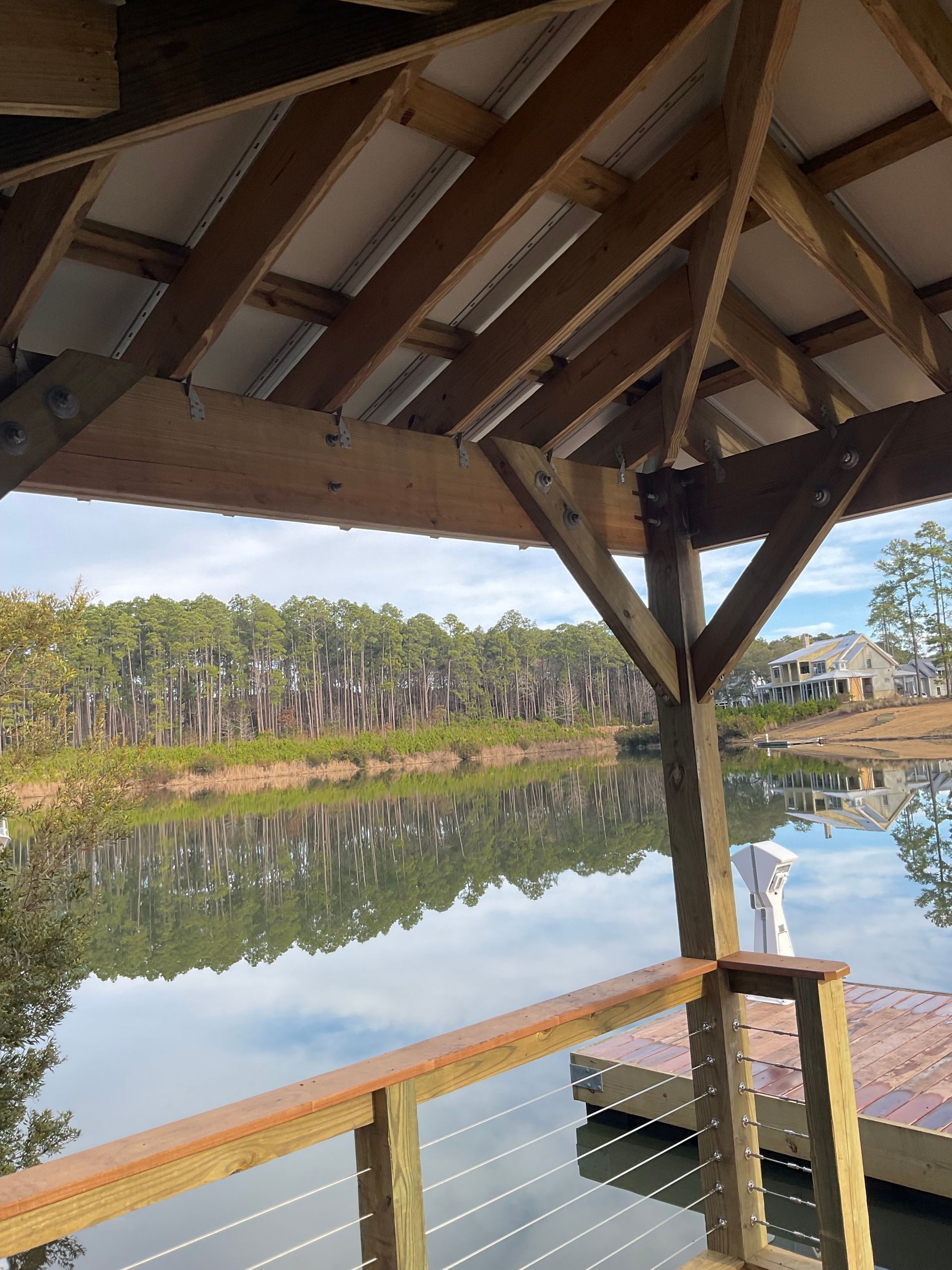 A wooden structure overlooking a body of water with trees in the background.