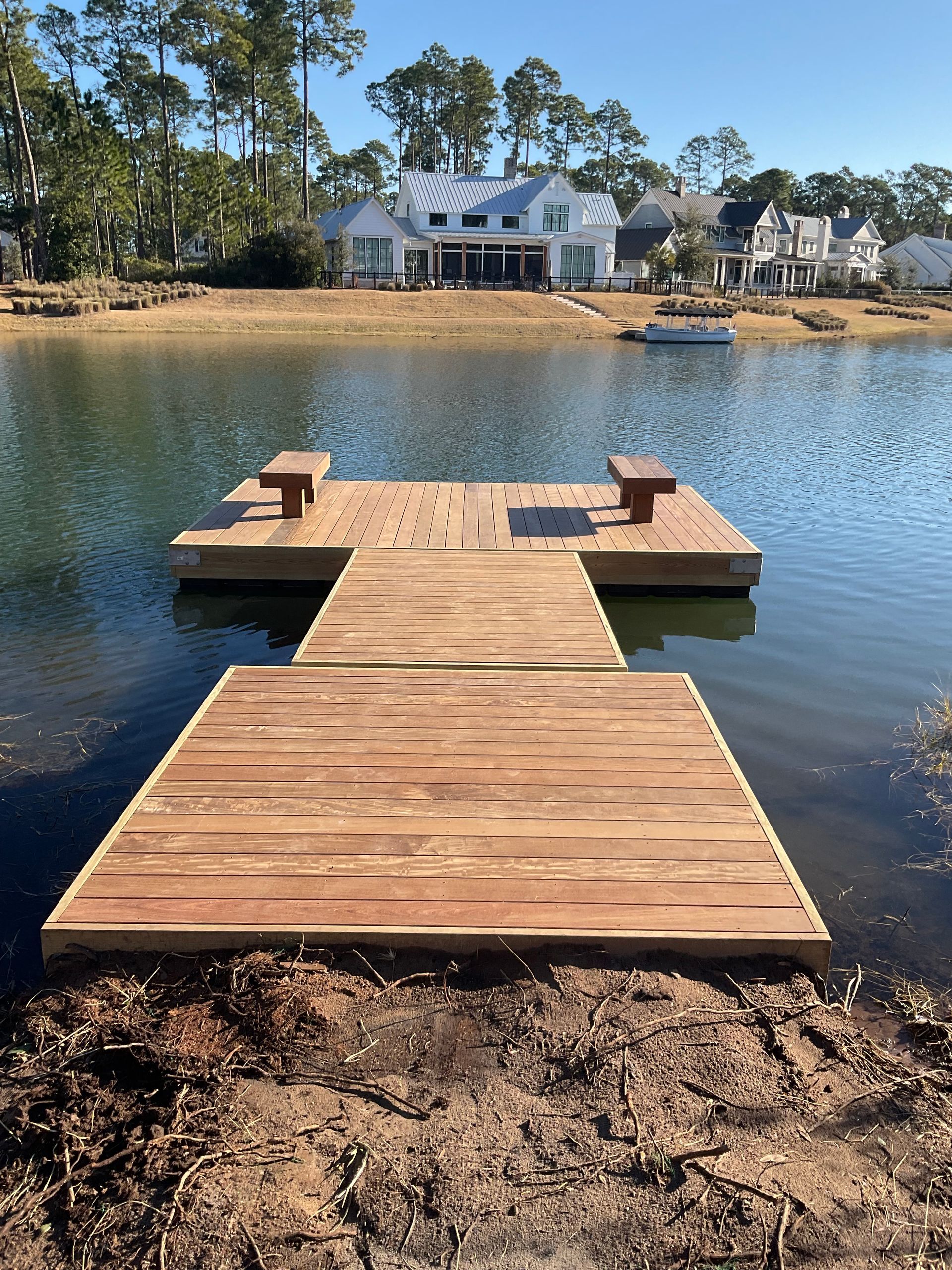A wooden dock in the middle of a lake with a house in the background.