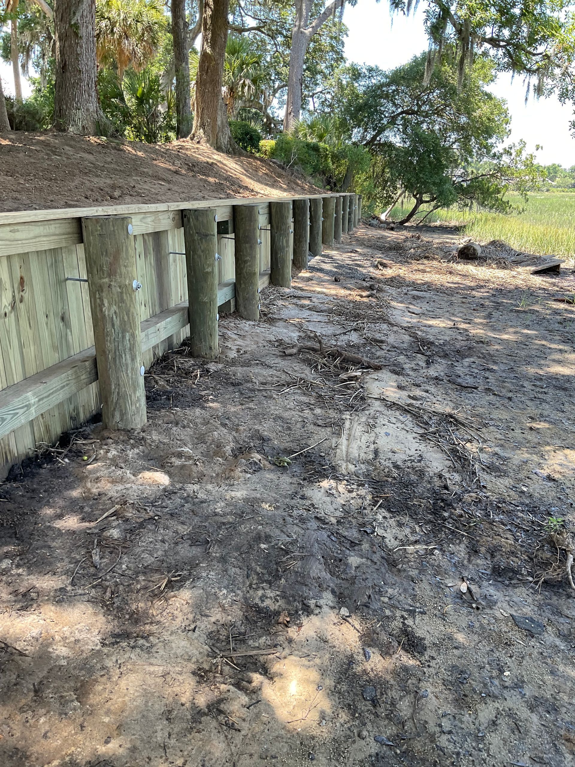 A row of wooden posts sitting on top of a dirt field.