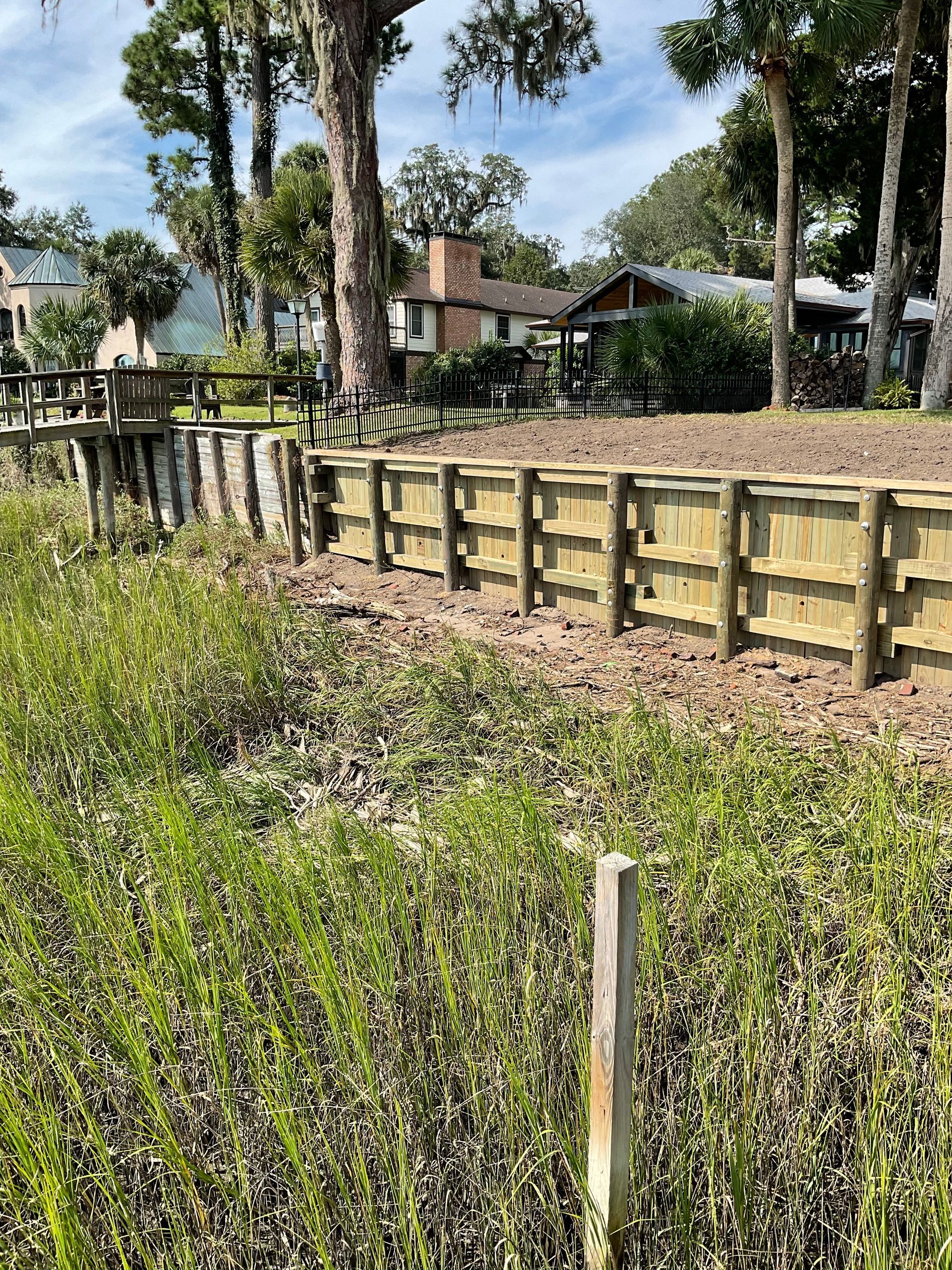 A wooden fence surrounds a grassy area next to a body of water.