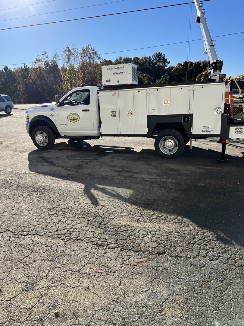 A white truck with a crane on top of it is parked in a parking lot.