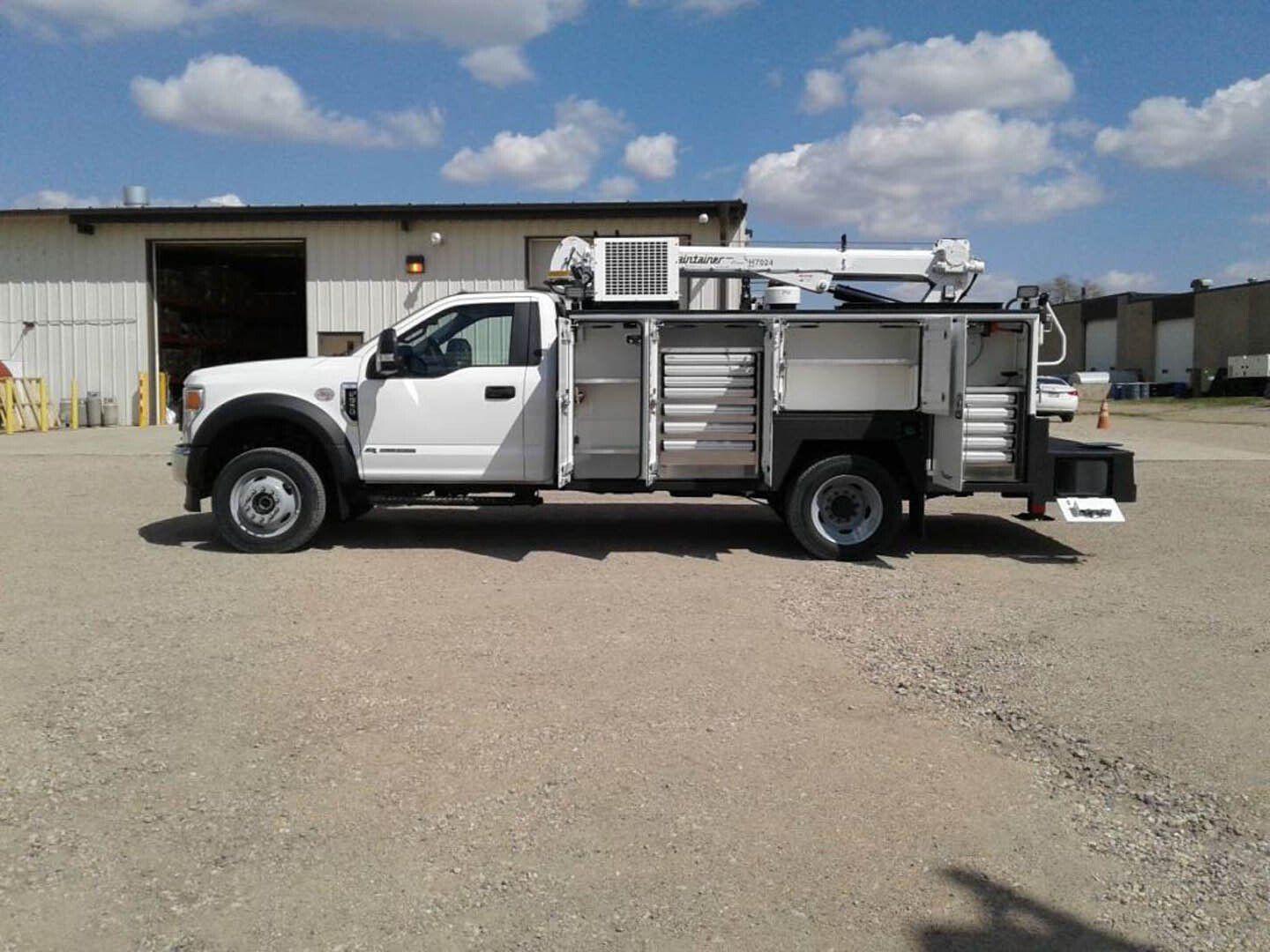 A white utility truck is parked in front of a building