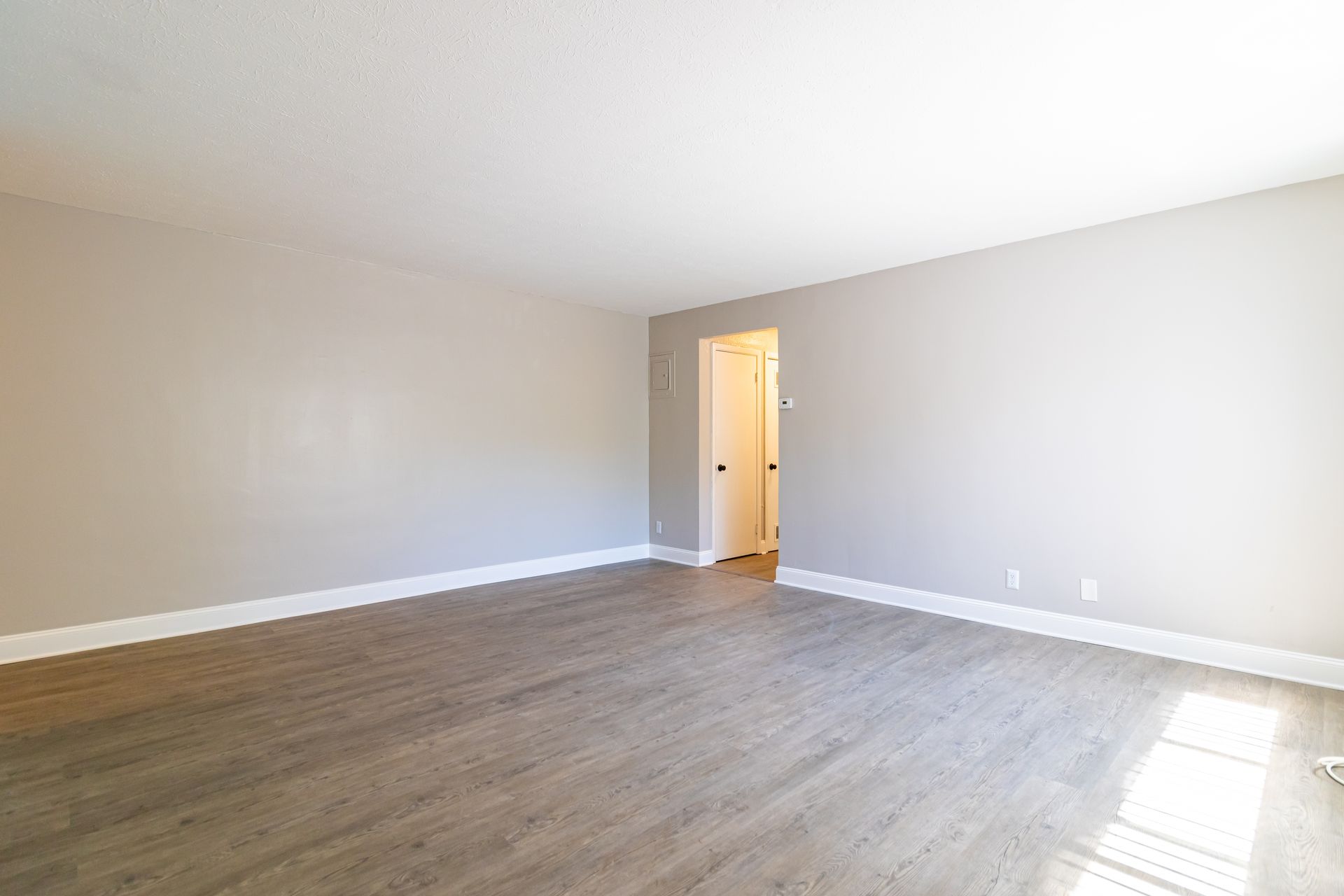 An empty living room with hardwood floors and gray walls.