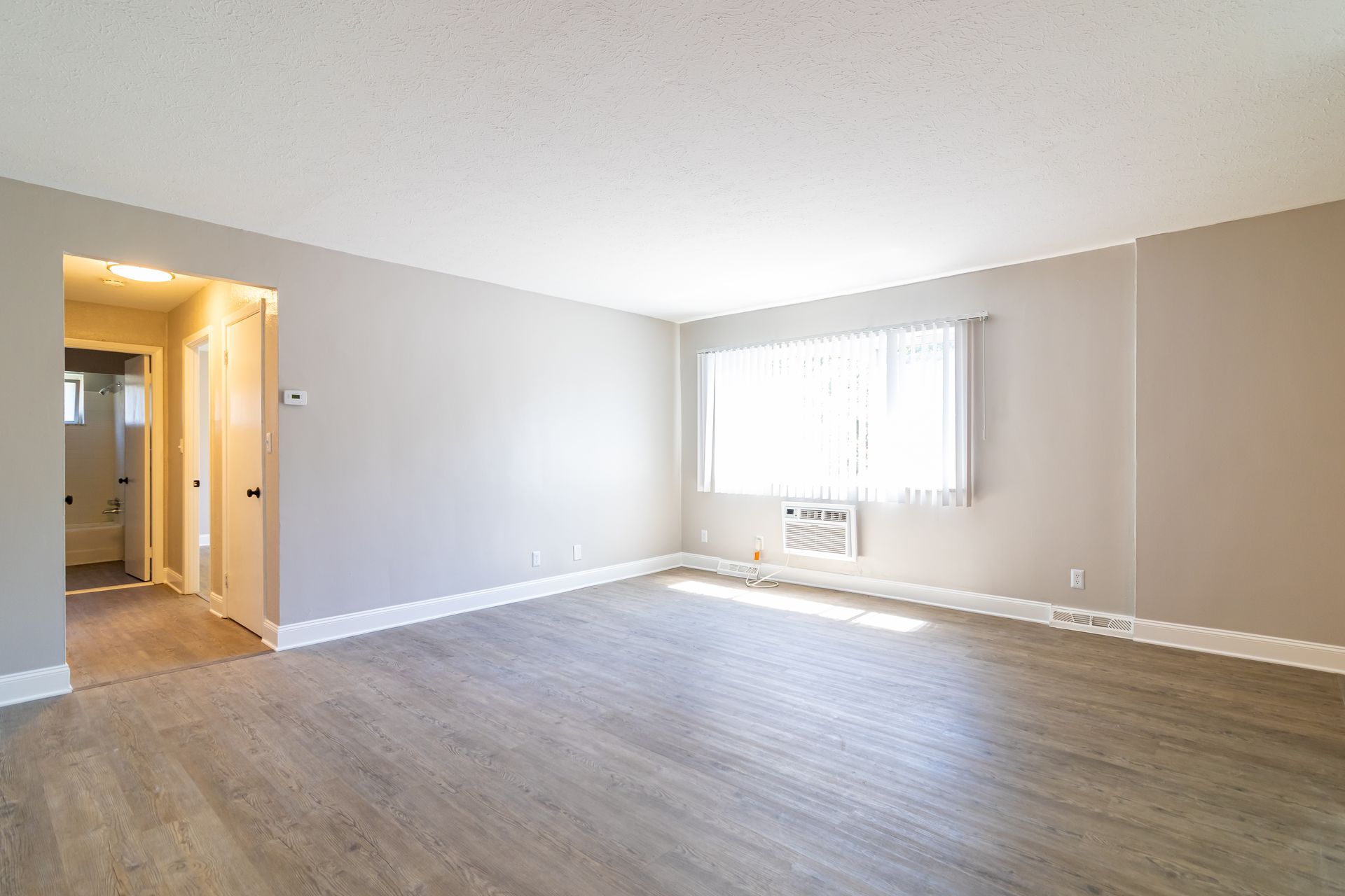 An empty living room with hardwood floors and a window.