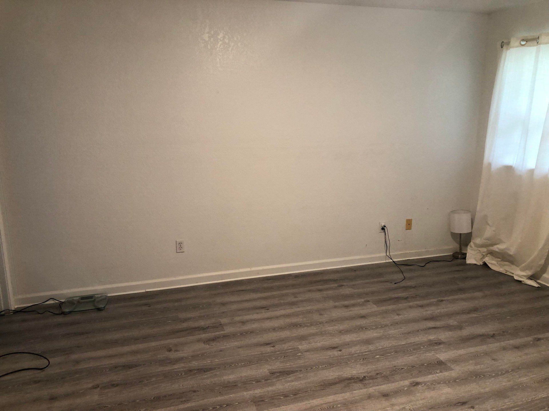 An empty living room with hardwood floors and white walls.