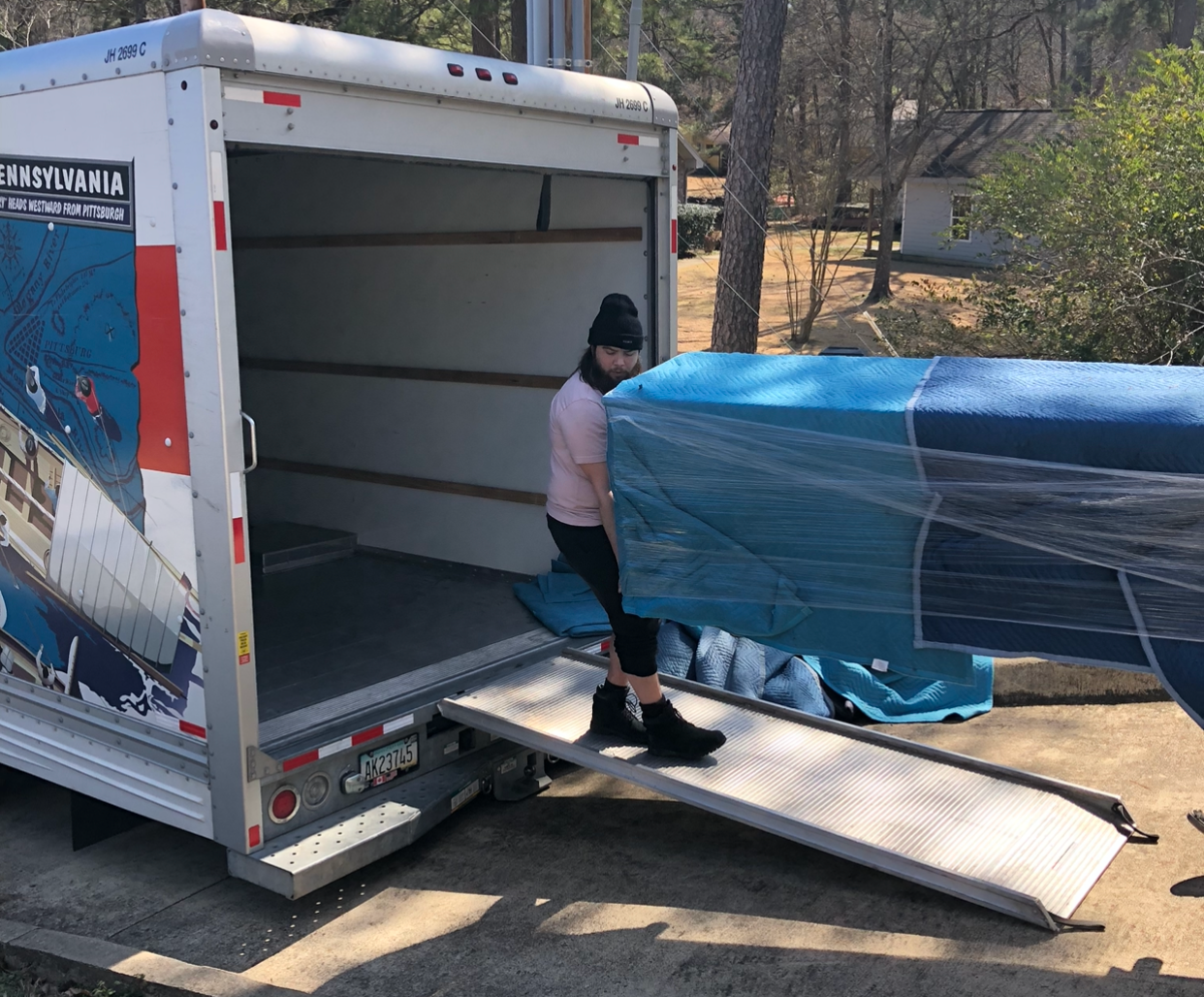 A man is loading a piano into a moving truck.