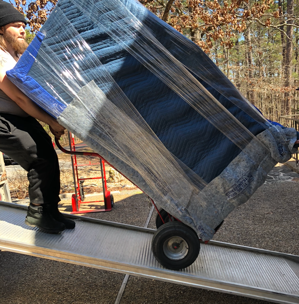 A man is carrying a large piece of furniture on a dolly