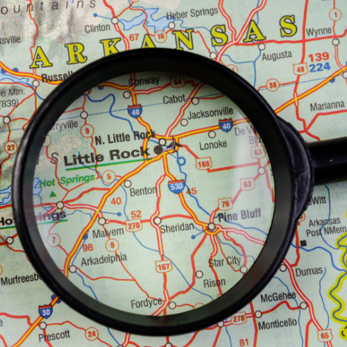 A magnifying glass on top of a map of arkansas