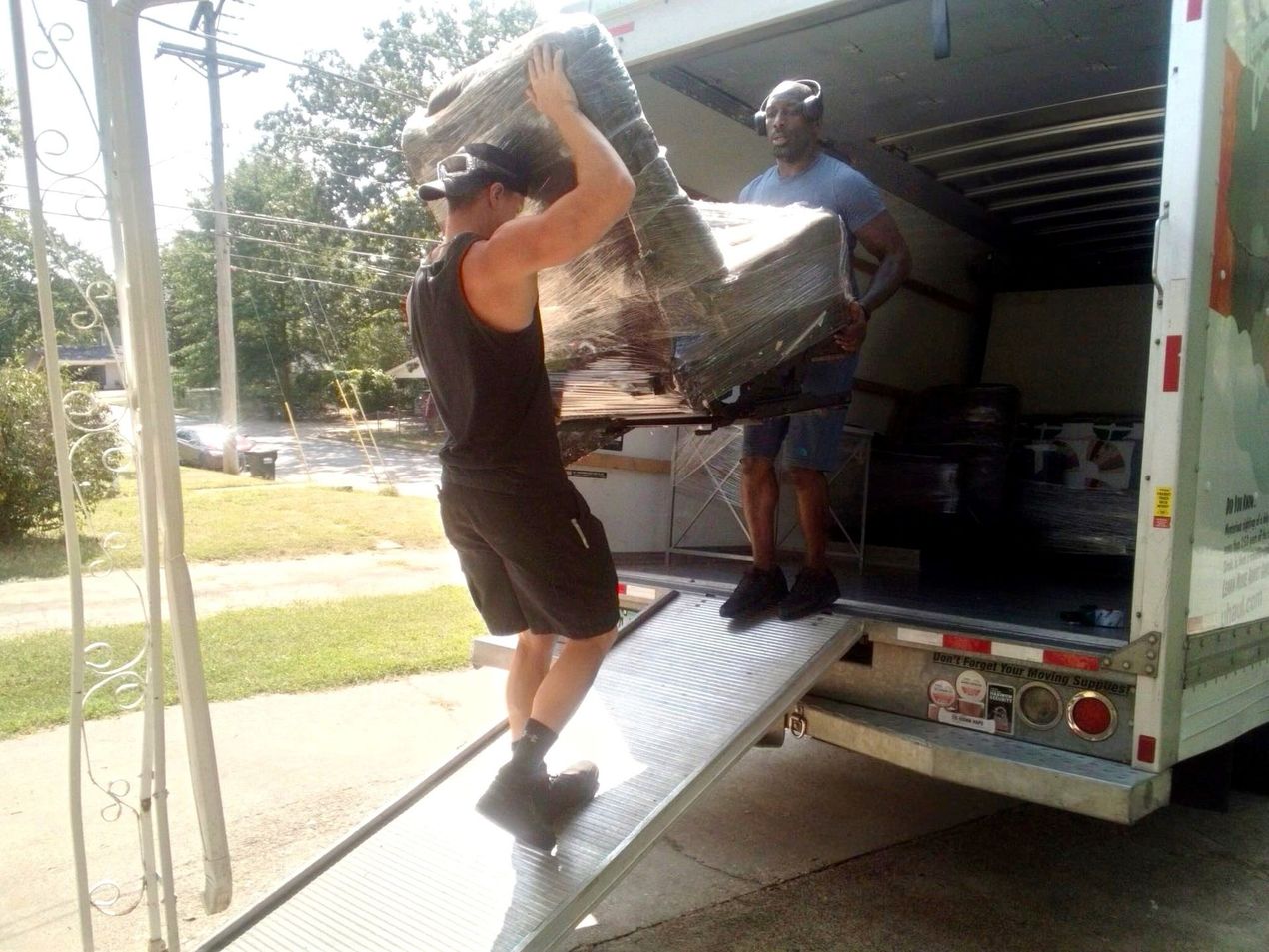 A man is carrying a large piece of furniture out of a moving truck.