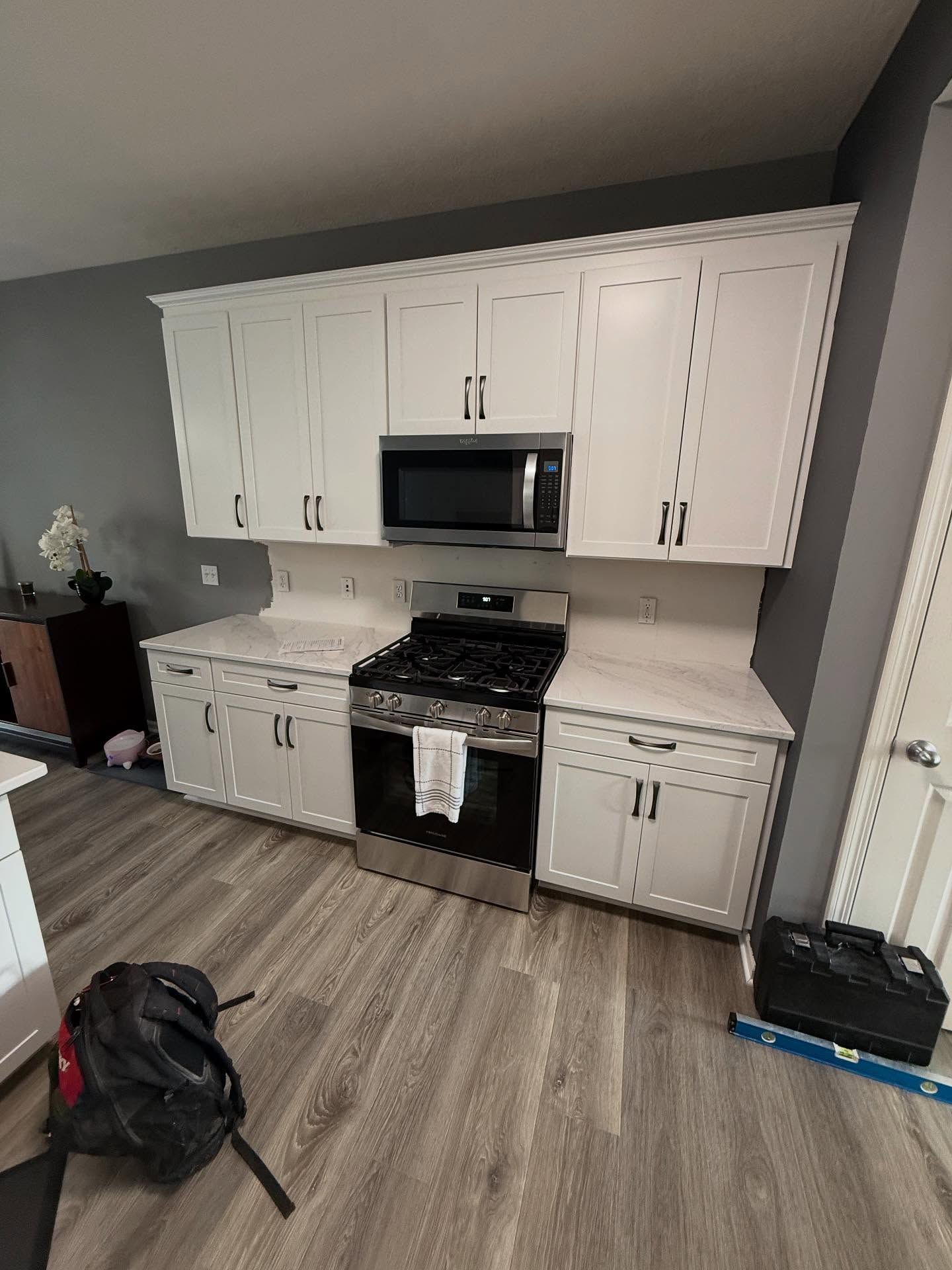 White kitchen cabinets and black stove with microwave in a small apartment kitchen.
