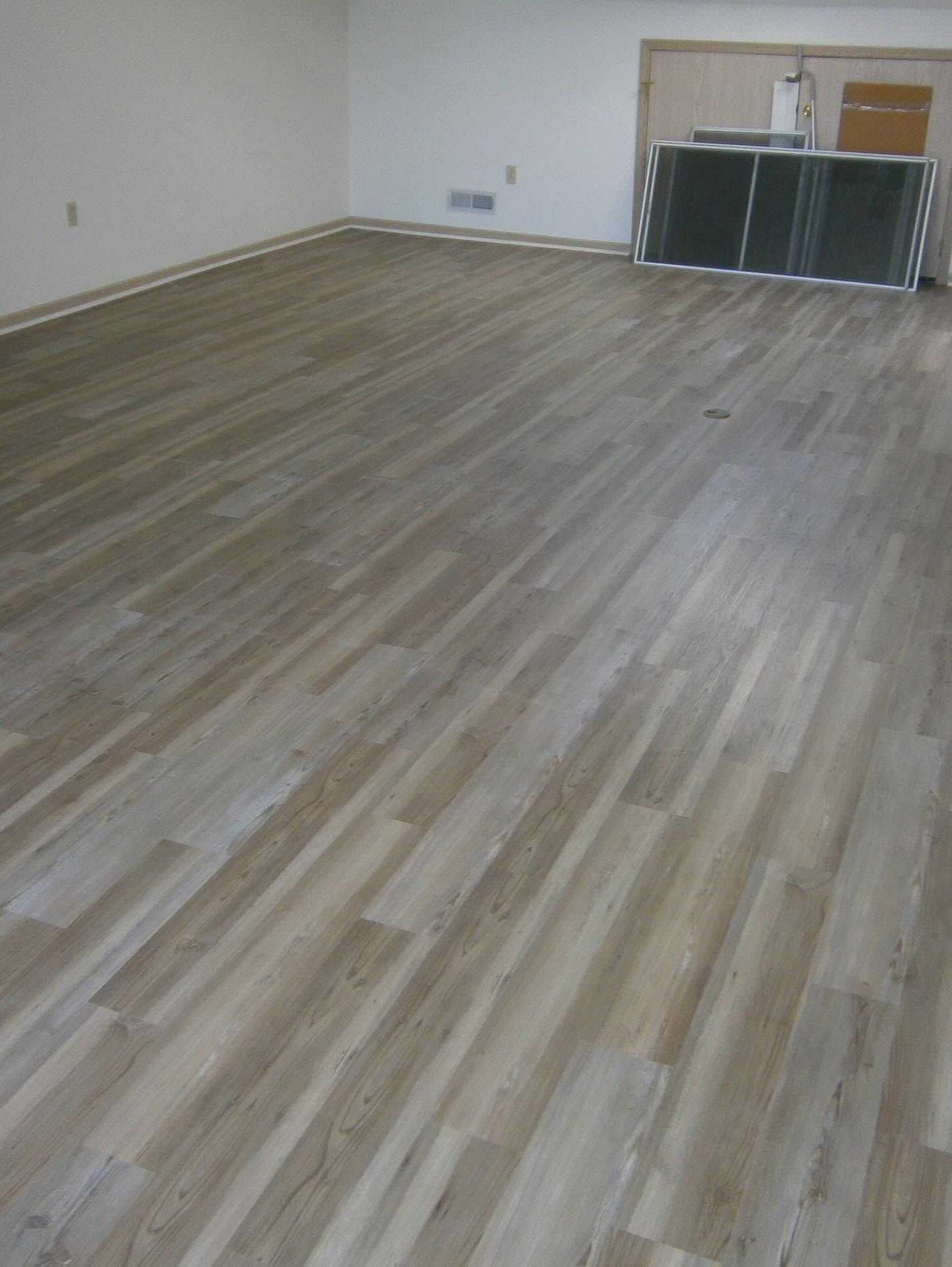 Empty room with light wood flooring and a cabinet along the far wall.
