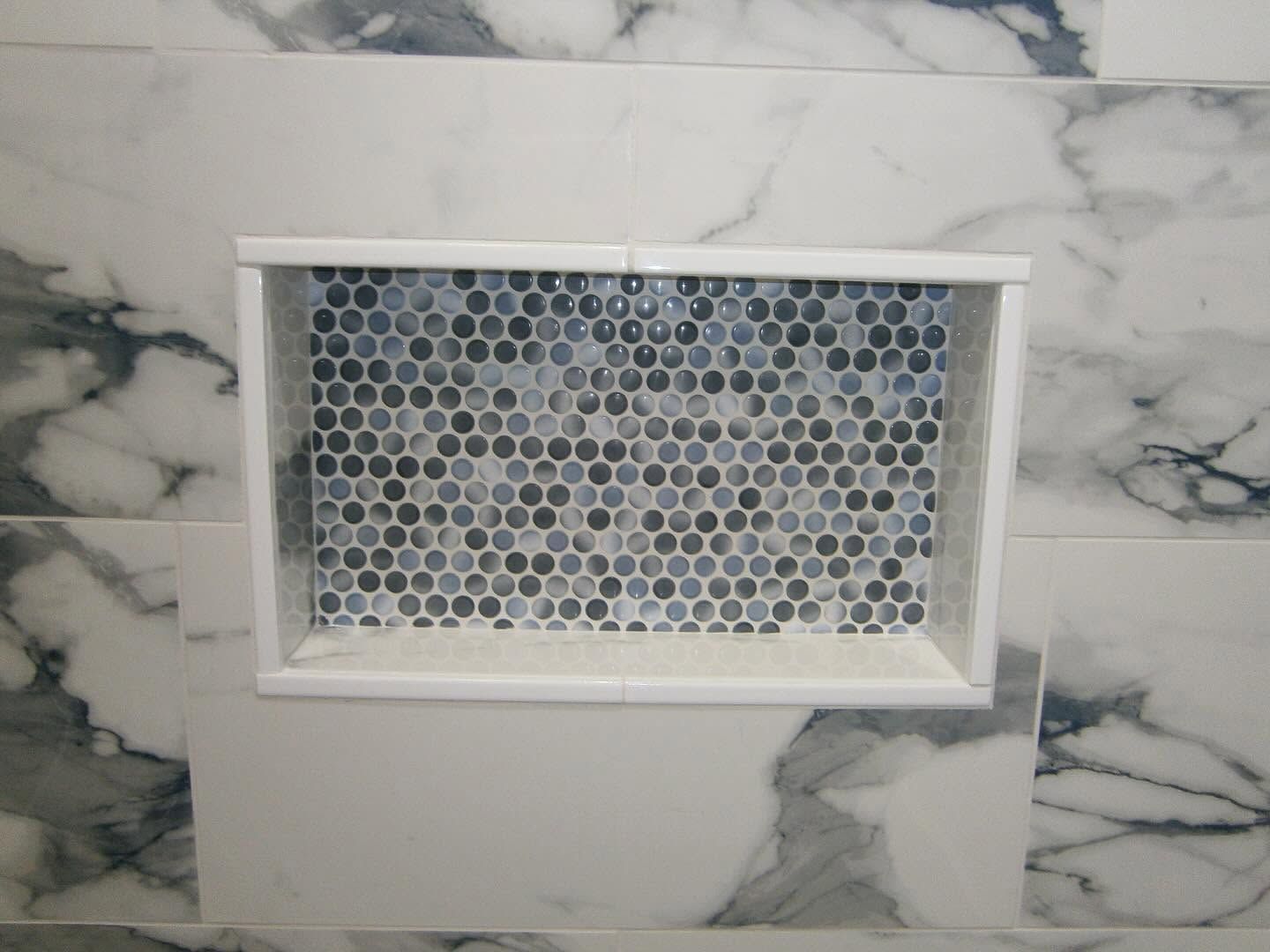 White-framed vent with hexagonal mesh set into a light gray marble-tiled wall.