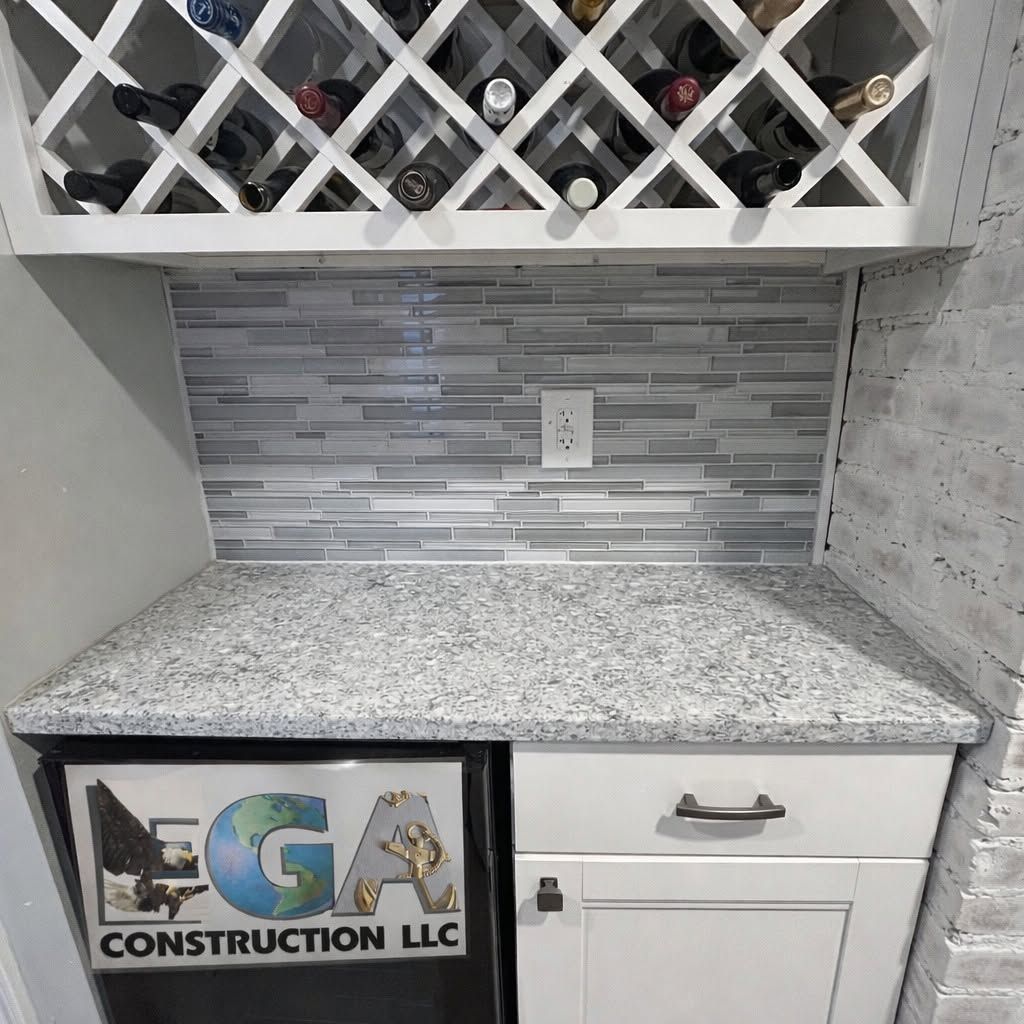 Granite countertop with gray tile backsplash, wine rack cabinet, and white drawers in a kitchen nook
