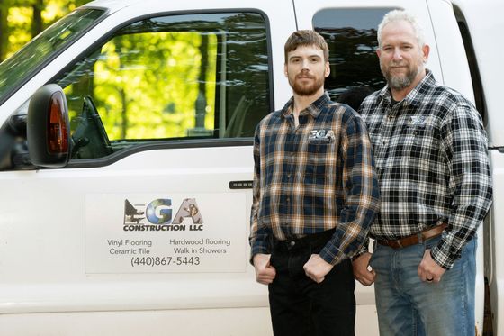 Two men standing beside a white work truck with a company logo on the door.
