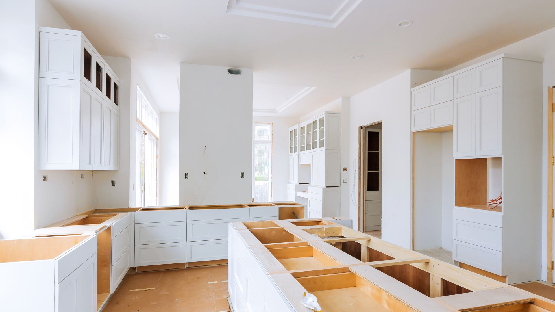 A kitchen under construction with white cabinets and wooden counter tops.