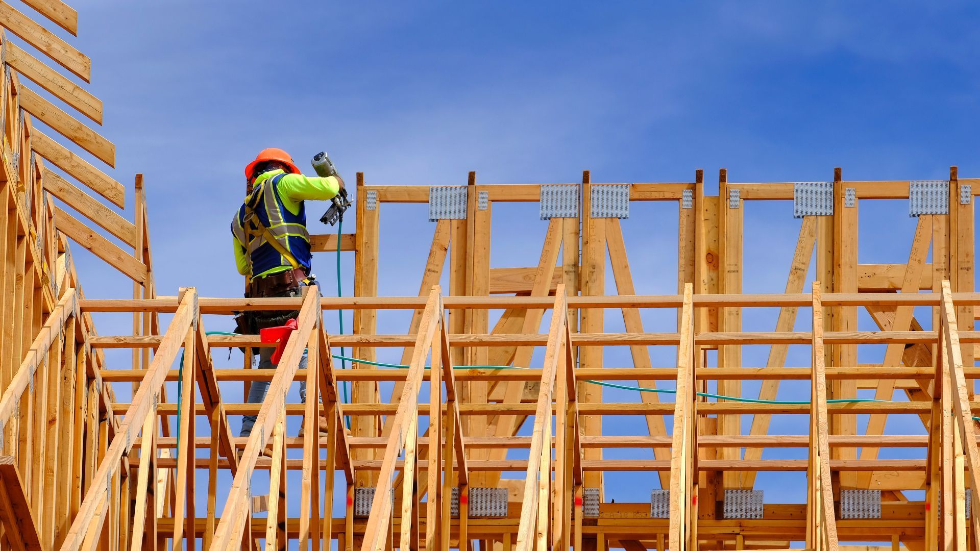 A construction worker is working on the roof of a building under construction.