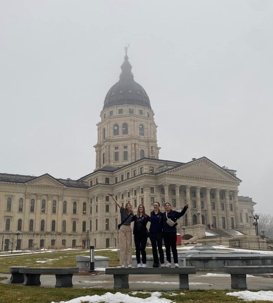 People posing in front of a large domed capitol building on a gray, foggy day.