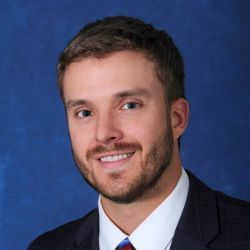 Portrait of a smiling man in a suit and tie against a blue background