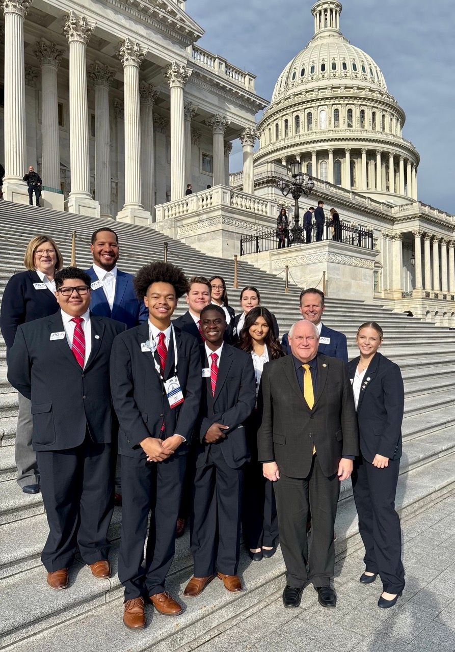 Group of officials posing on Capitol steps with the U.S. Capitol dome in the background