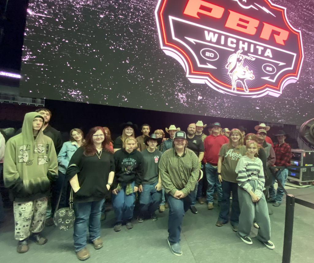 Group of people posing indoors in front of a large PBR Wichita event sign.