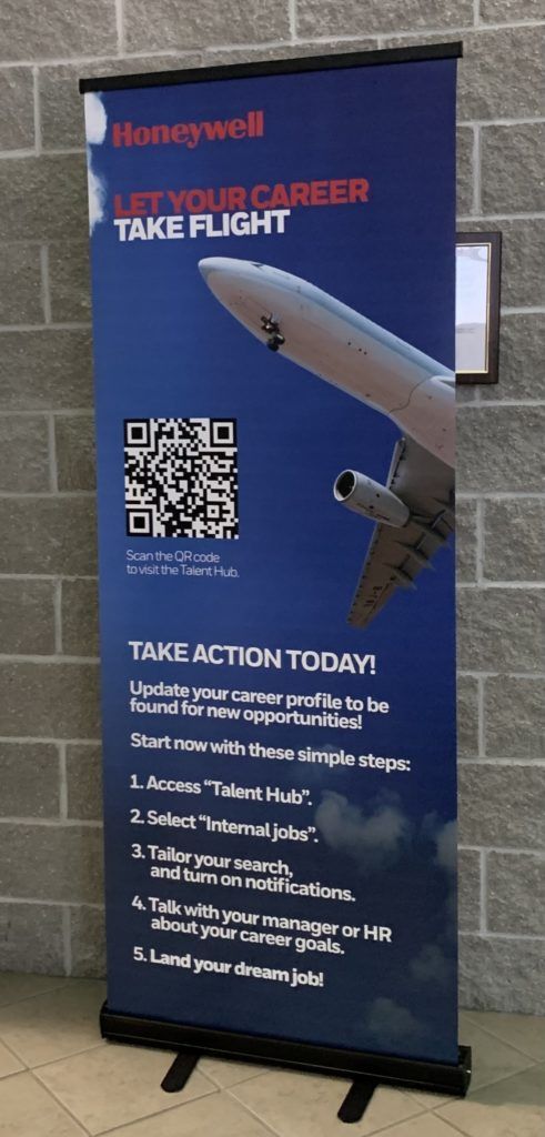 Blue Honeywell airport banner reading “YOUR CAREER TAKE FLIGHT” with airplane wing graphic and QR code