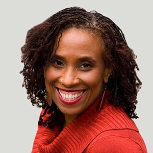 Smiling woman with curly hair wearing a red sweater against a light gray background