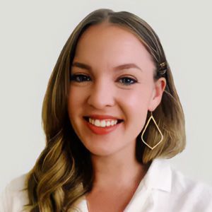 Smiling woman with shoulder-length hair wearing a white blouse and gold geometric earrings