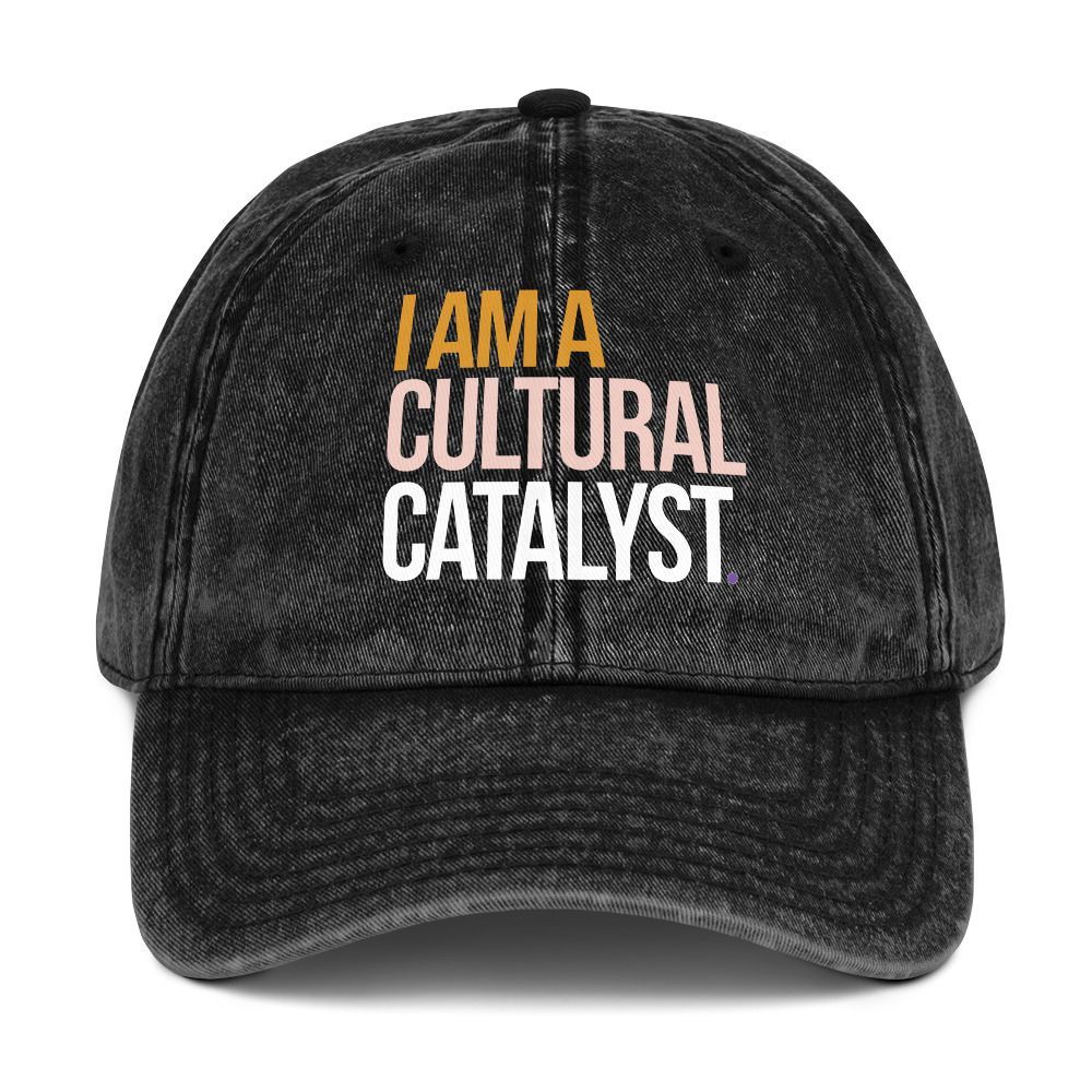 Black baseball cap with “I AM A CULTURAL CATALYST” text in orange and white.