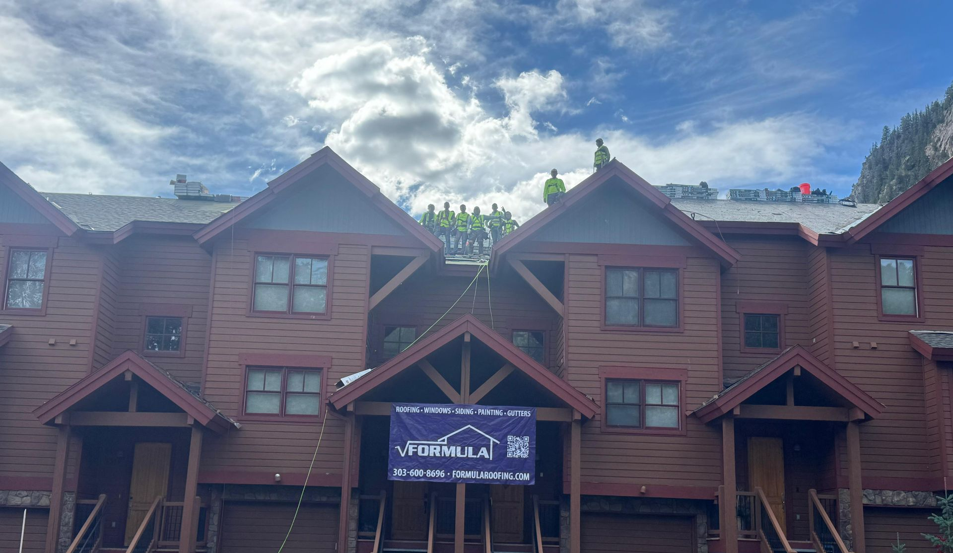 Two workers in safety gear repairing a gray roof on a house Two workers in safety gear repairing a gray roof on a house