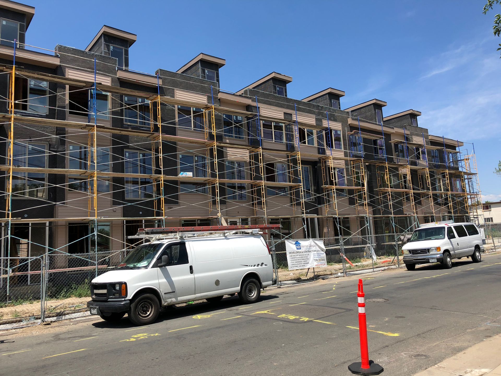 A white van is parked in front of a building under construction.