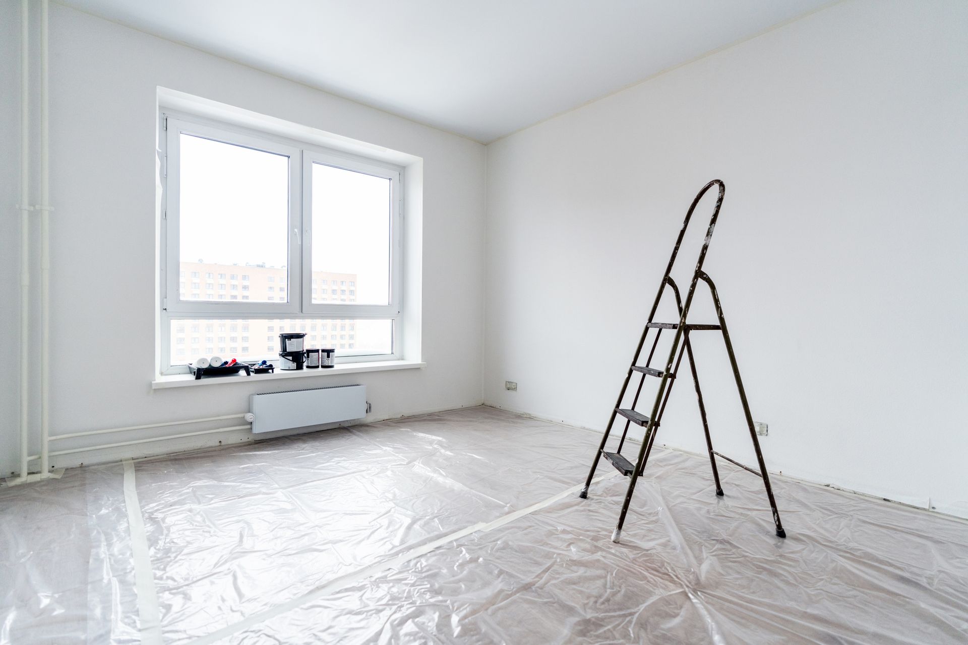 An empty room prepared for painting services, with the floor covered in polythene.